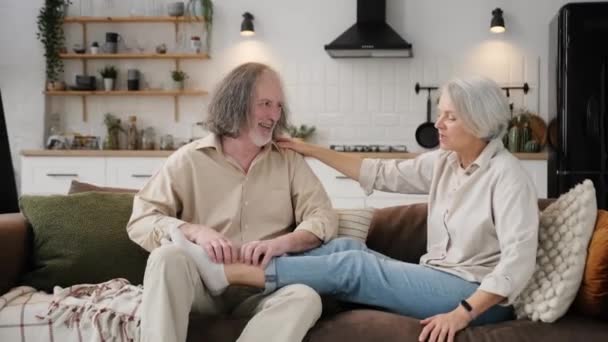 幸せな夫婦はソファの上に座ってマッサージをします 思いやりのある夫が妻をマッサージし — ストック動画