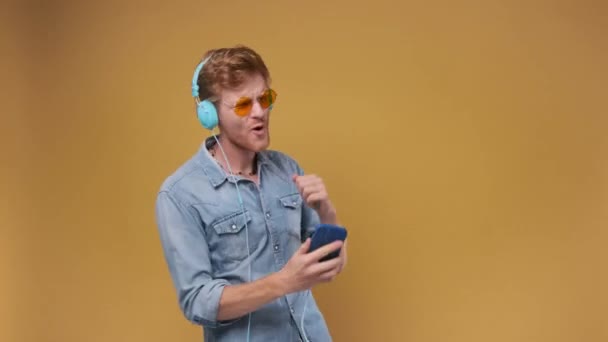 时尚的男人手握智能手机 在棕色工作室的背景下听音乐 — 图库视频影像