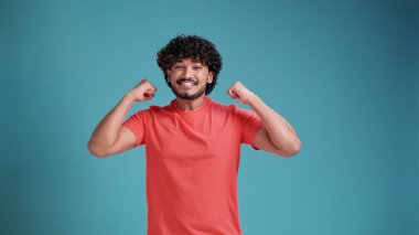 Aşırı heyecanlı, aşırı neşeli, sakallı, evet jestleri yapan, mavi stüdyo arka planındaki zaferi karşısında hayrete düşmüş Latin bir adam.