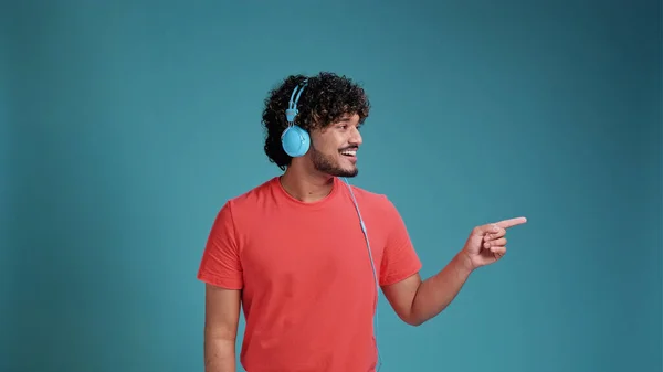 Swarthy Man Listening Music Using Headphones Coral Shirt Blue Studio — Stock Photo, Image