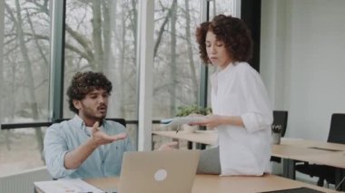 İki çok ırklı çalışan, bir Afro-Amerikalı kadın ve laptopun yanındaki Latin bir adam kötü yapılmış bir iş hakkında tartışıyorlar. CEO memnun değil ve astlarına kızgın.
