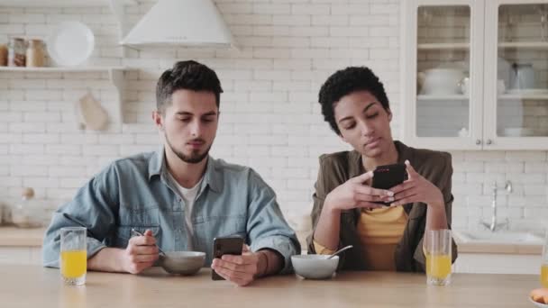 千年情侣沉迷于智能手机 他们互相忽视 在家里吃早饭 严肃的年轻人使用移动应用程序或在线检查社交网络 小工具过度利用 — 图库视频影像