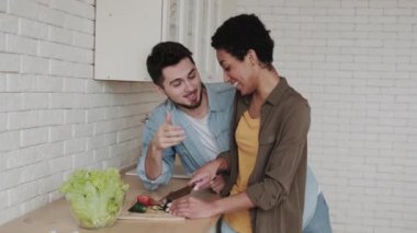Genç çift sağlıklı yemek pişirirken ve salata hazırlarken eğleniyor. Sağlıklı beslenme ve vejetaryenlik kavramı.