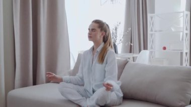 Lotus poz kanepe oturma odasında, meditasyon, çekici kız stres kabartma kavramı, sağlıklı iyi alışkanlık pratik yoga, evde Kapalı gözlerle oturan huzurlu genç kadın