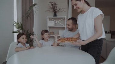 Annem iki kızı olan ailesine pizza ısmarlıyor. Parlak bir iç mekanda aile yemeği