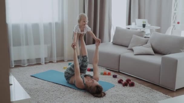 Mama Ćwiczy Dzieckiem Domu Wychowuje Dziecko Nogach Leżąc Karemacie — Wideo stockowe