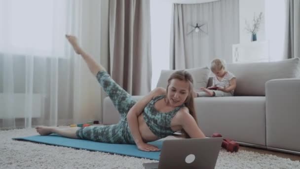 Mama Wykonuje Ćwiczenia Podnoszeniem Nóg Leżąc Karemacie Domu Obok Dziecka — Wideo stockowe