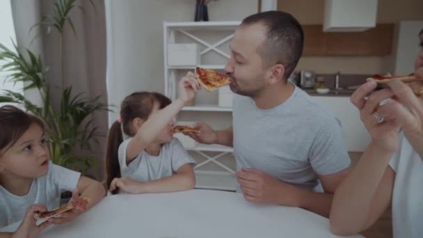 2人の娘がいる家族がピザを食べる 明るい家のインテリアで家族の食事 — ストック動画