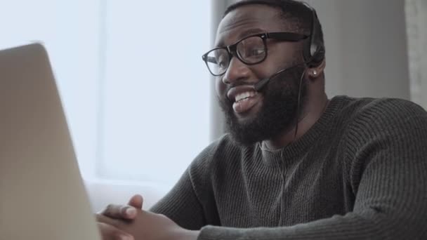 ヘッドセットのアフリカ系アメリカ人の男性コールセンターエージェント ヘッドフォンでノートパソコンの黒人男性を使用してオンラインでビジネスクライアントを相談 — ストック動画