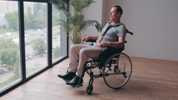 Старший Взрослый Мужчина Сидит Инвалидной Коляске Возле Окна Глядя Улицу — стоковое видео