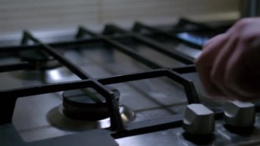 Mutfak ocağını açan kişi gaz ocağını yakıyor ve doğal gaz mavi alevle tutuşuyor ve sonra da kapanıyor..