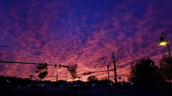 在佐治亚州令人目瞪口呆的夕阳西下 云彩映出桃色 粉色和紫色 这些云彩映衬着皇家蓝色的夜空 提供了一个可爱的渐变 前面有一个交叉口 包括灯 电线和汽车 — 图库照片