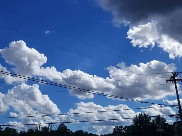 Глубокое Голубое Небо Пушистыми Белыми Облаками Линиями Электропередач Растянувшимися Переднем — стоковое фото