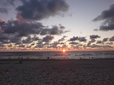 Sahilde güzel bir gün batımı ve gökyüzünde bulutlar olan son insanlar.