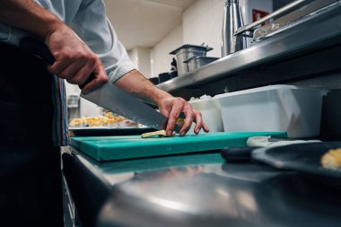 Profesyonel bir mutfakta enginar kesiyor.