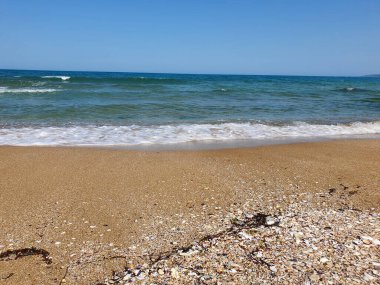 Berrak Gökyüzüne Karşı Sakin Deniz 'in Manzarası. Kumsal ve deniz. Sahilde dalgalar