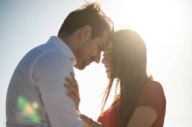 Romantik çift arka planda hoş bir ışık efektiyle baş başa kucaklaşıyorlar.