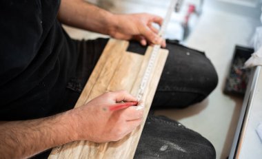 Marangoz bir fayansı mezurayla ölçüyor.