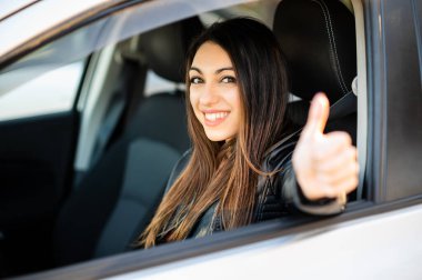 Arabasında güvenle gülümseyen genç bir kadın.