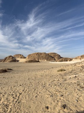 Sina, Mısır 'daki Kızıl Kanyon' da kırmızı kumtaşı oluşumları. Resimde engebeli kaya dokuları, çöl kumları, mavi gökyüzü, manzaranın doğal güzelliğini ve jeolojik özelliklerini vurguluyor.