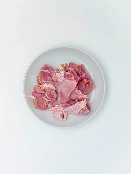 Beyaz tabakta çiğ tavuk filetosu. Beyaz arka planda izole edilmiş. Üst manzara, düz uzanma.