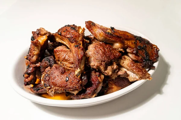 Beyaz arka planda, oval beyaz kâsede ızgara kuzu pirzolası..