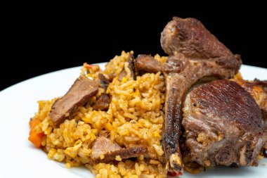 Beyaz tabakta ızgara kuzu etli ev yapımı pilav, siyah arka planda izole edilmiş. Yan görünüm.