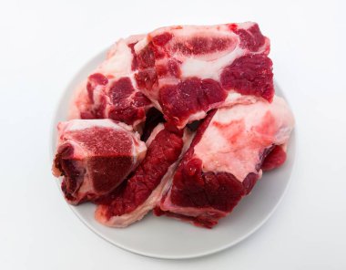 Beyaz tabakta çiğ pirzola. Kopya alanı olan beyaz bir arkaplanda izole edilmiş. Yakın çekim görünümü.