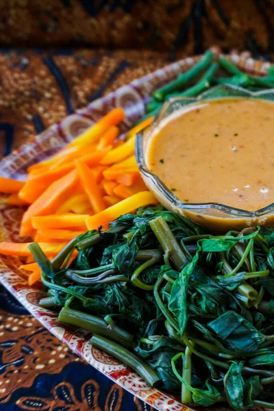 Pecel sayur geniş bir tabakta sığ bir alan derinliğinde. Pecel sayur veya sebze karışımı Endonezya 'da geleneksel bir yemektir, özellikle Doğu Java' da, çeşitli sebzeler ve fıstık sosu ile birlikte..