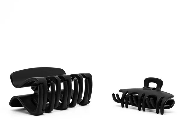 Beyaz zemin üzerinde izole edilmiş iki siyah plastik saç tokası ya da saç tokası. Saç aksesuarları.