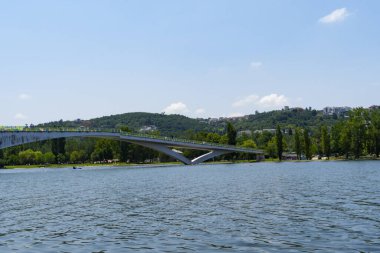Portekiz 'in Coimbra kentindeki Mondego Nehri manzarası, açık bir gökyüzünün altında, ağaçlar ve yaya köprüsü var. Peyzaj arkaplanı ve duvar kağıdı.