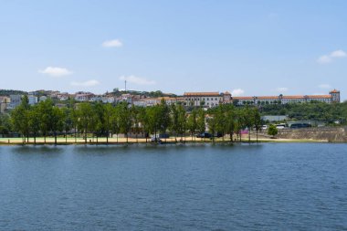 Mondego Nehri ve Coimbra Şehri 'nin açık bir gökyüzü altında, ağaçlar ve binalarla manzarası. Peyzaj arkaplanı ve duvar kağıdı.