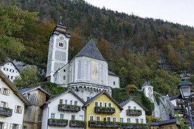 Hallstatt Katolik Kilisesi 'nin büyüleyici manzarası sonbaharda ormanlık bir dağ yamacına kurulmuştur..