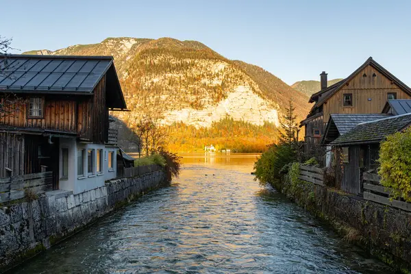 Durgun bir dağ deresi kırsal ahşap evler arasında akar, batan güneşin altın renklerini yansıtan parlayan bir göle götürür..