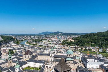 Salzburg, Avusturya 'nın havadan görünüşü, tarihi barok mimarisi, kilise kubbeleri ve Salzach Nehri' nin şehirde kıvrılarak ilerlemesi, açık bir yaz gününde arka planda dağlarla birlikte..
