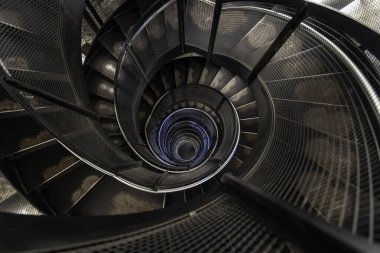 Metal parmaklıklar ve endüstriyel tasarım ile modern spiral merdivenlerin soyut görüntüsü, yukarıdan çekildi..