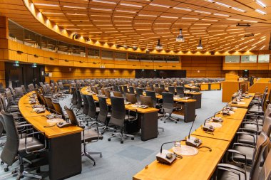 Kavisli ahşap masaları, siyah sandalyeleri ve münferit mikrofonları olan boş modern konferans odası, resmi bir düzende uluslararası toplantılar veya hükümet zirveleri için tasarlandı..