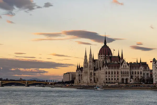 Macaristan 'ın Budapeşte kentindeki Tuna Nehri kıyısındaki renkli gökyüzü ve manzaralı Macar Parlamentosu binasının çarpıcı gün batımı manzarası.