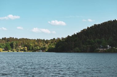 Göl manzarası ve tepedeki ağaçlar.