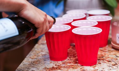 Bardakta kırmızı şarap olan şişeyi kapat.