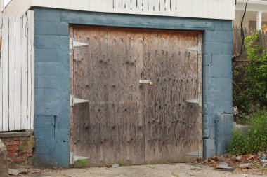 Eski paslı bir kapı, tuğla bir kapı ve mavi bir gökyüzü.