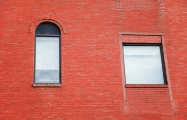 Arka planda kırmızı tuğla duvar olan kırmızı tuğlalı pencereler