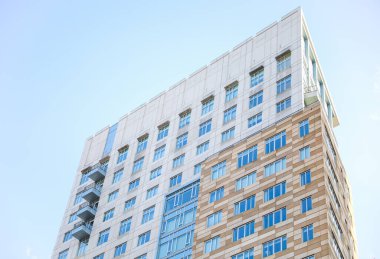 Mavi gökyüzü ve bulutları olan modern apartman cephesi.