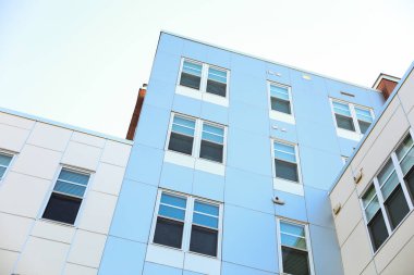 Güneşli bir günde mavi gökyüzü olan modern apartmanlar. Bir apartmanın ön cephesi