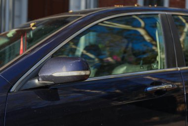 Güneşli bir günde şehir caddesinde sarı ışıkları olan siyah bir arabanın yakın çekimi.