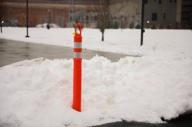 Beyaz tuğlalı bir duvarla caddede kar külahı.