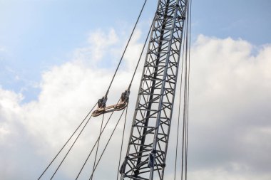 Mavi gökyüzünün arka planına karşı bir vinçte iki inşaat işçisi. yüksek kaliteli fotoğraf.