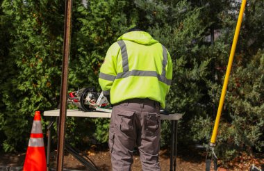 Koruyucu kasklı bir işçi, elinde tornavidayla bir inşaat alanının arka planında tornavida olan bir işçi.