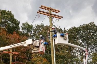 Bir adam elektrik direğini tamir ediyor.