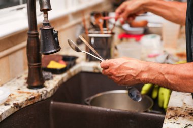 Beyaz tişörtlü bir adam bıçak kesiyor ve mutfak masasında pasta pişiriyor, yemek pişiriyor.